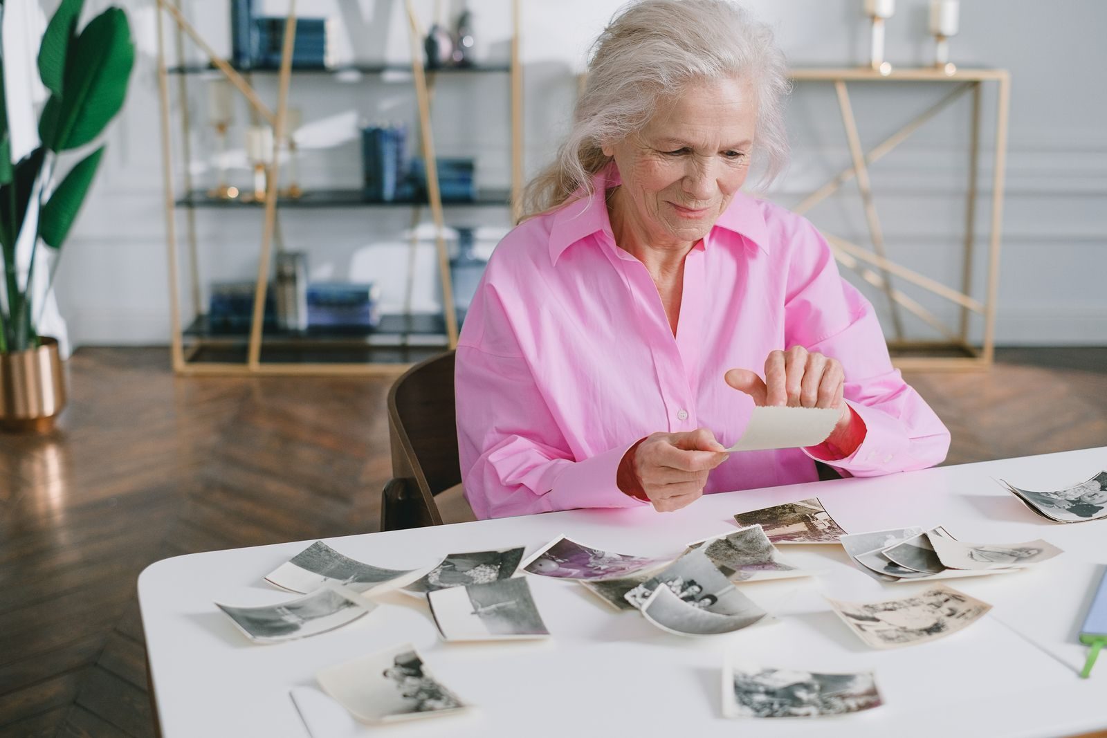 Older woman looking through old family photographs at her dining table at home