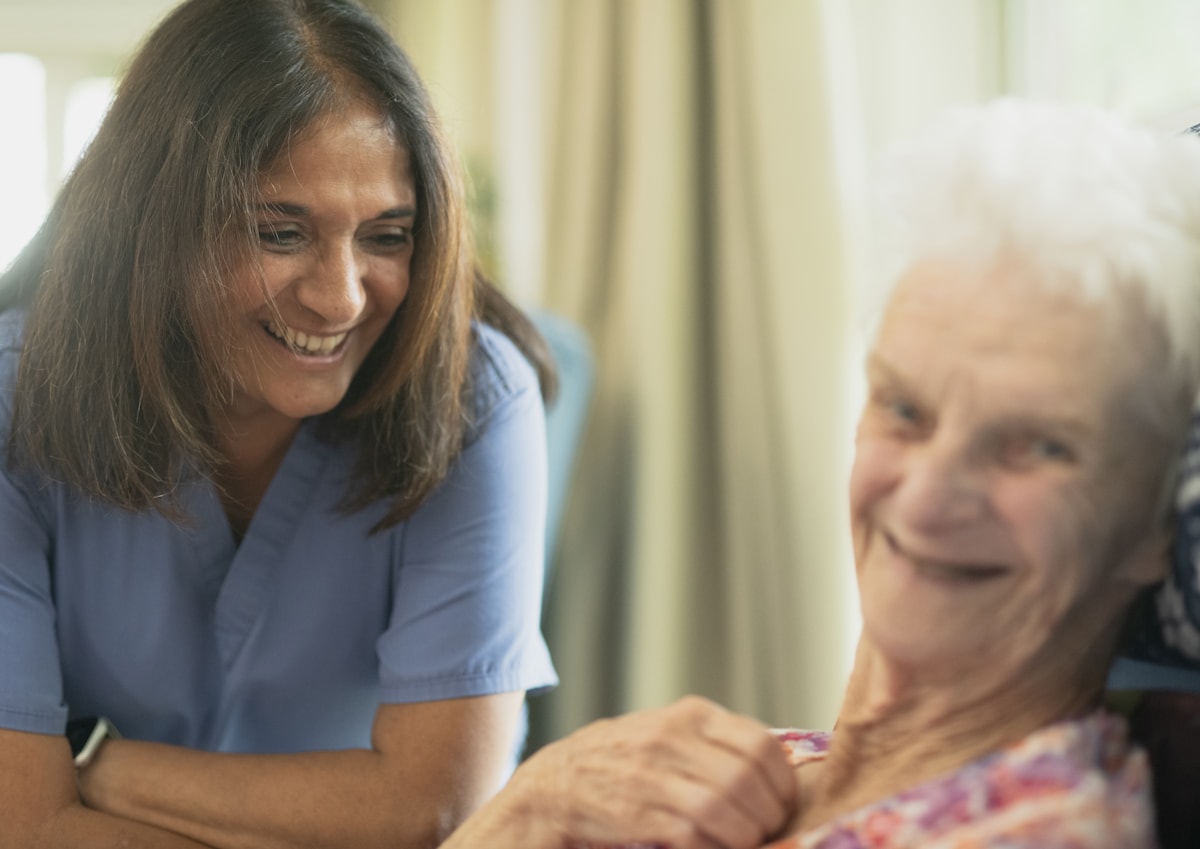 Caregiver smiling with an older adult during personal care support