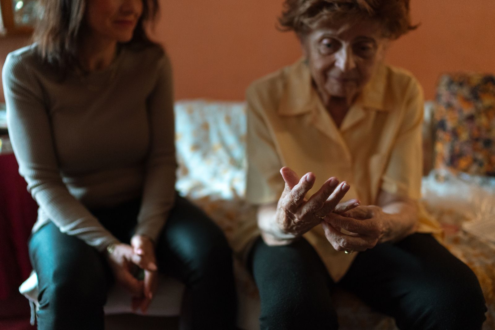 Caregiver sitting with an older woman on her sofa, keeping her company at home