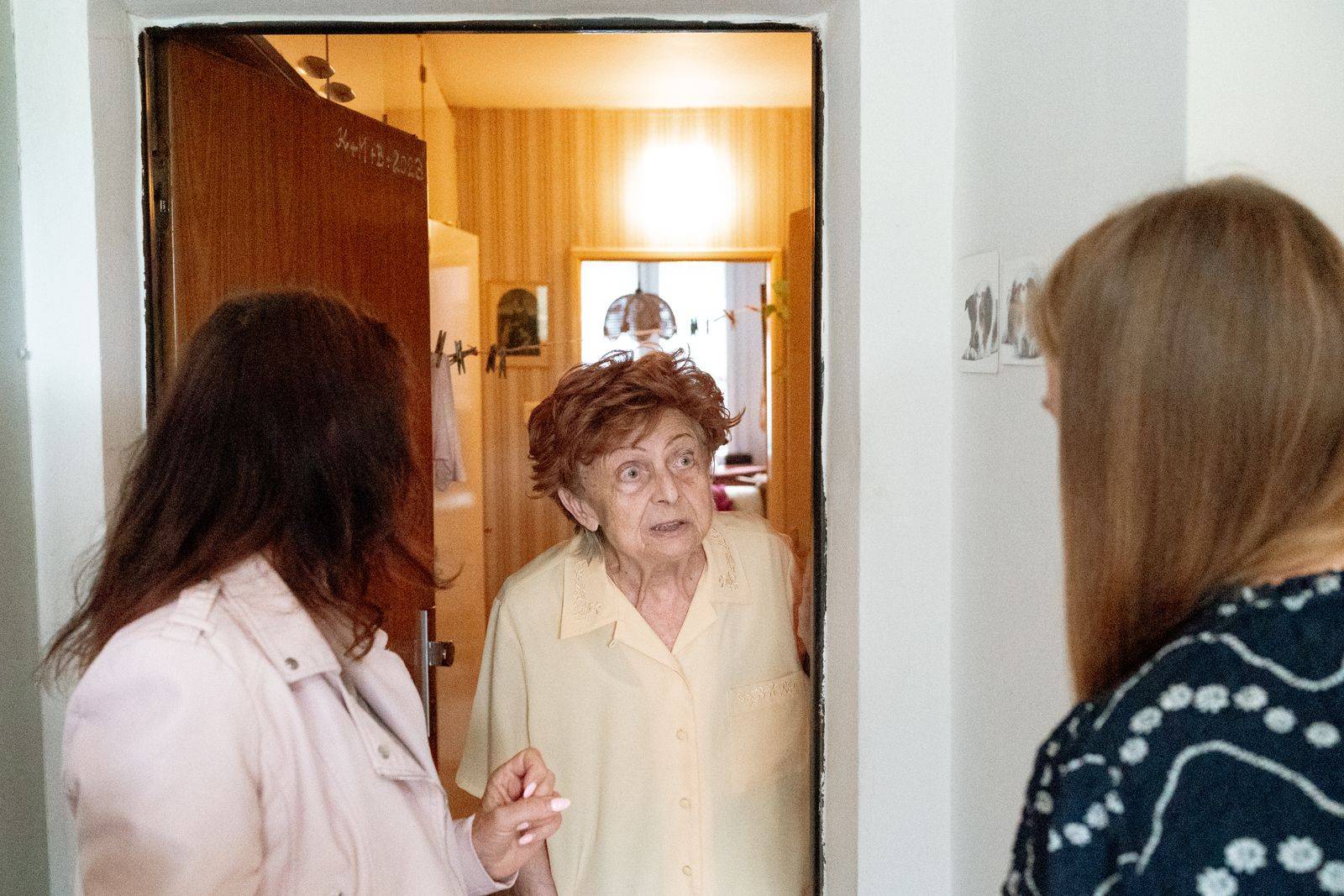 Two caregivers at the front door of an older woman's apartment during a home visit