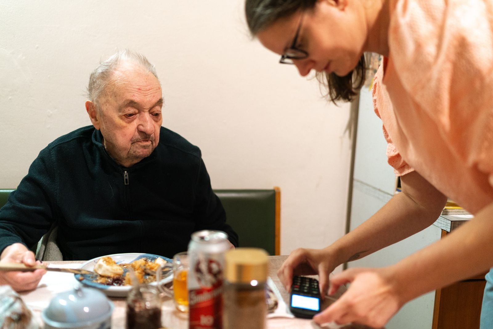 Caregiver serving lunch to an older man at his kitchen table at home