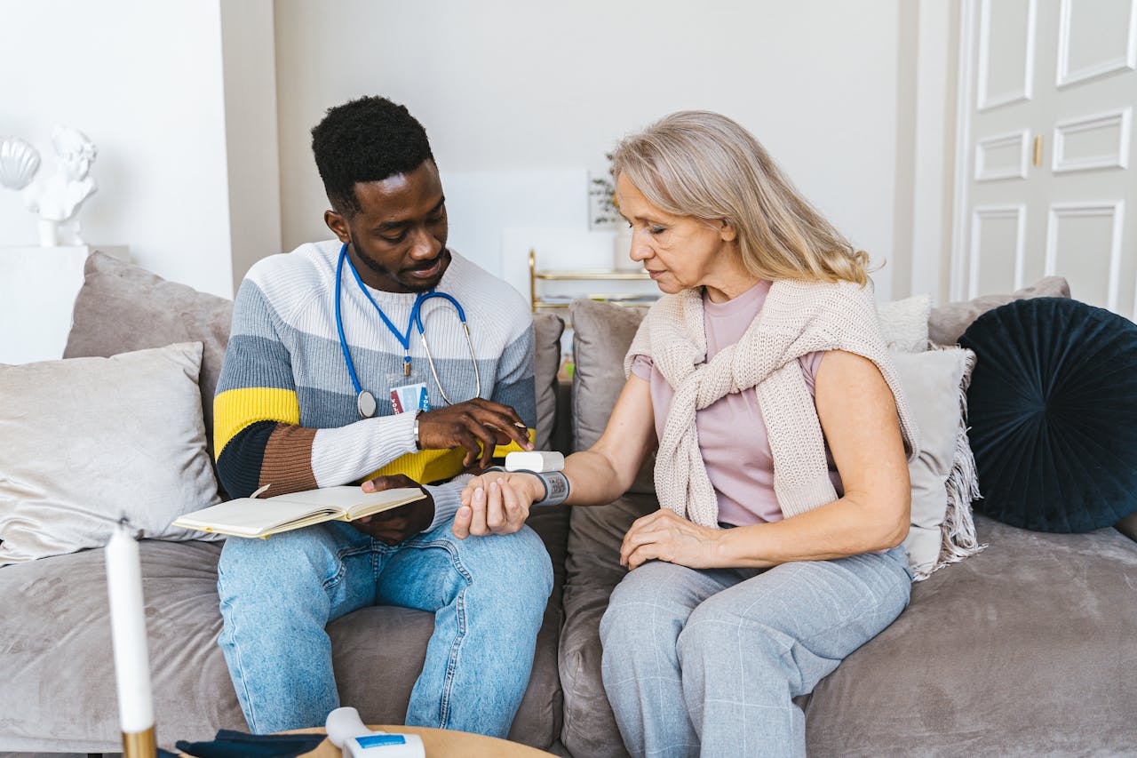 Healthcare professional checking blood pressure of elderly woman in a cozy indoor setting.