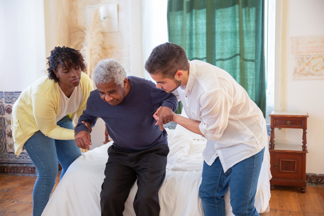 hero-gallery-02 An elderly man receiving assistance from caregivers in a cozy home environment.